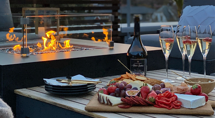Stemningsfoto fra terrassen til @villalille, med bålpanne, bobler, ost og kjeks
