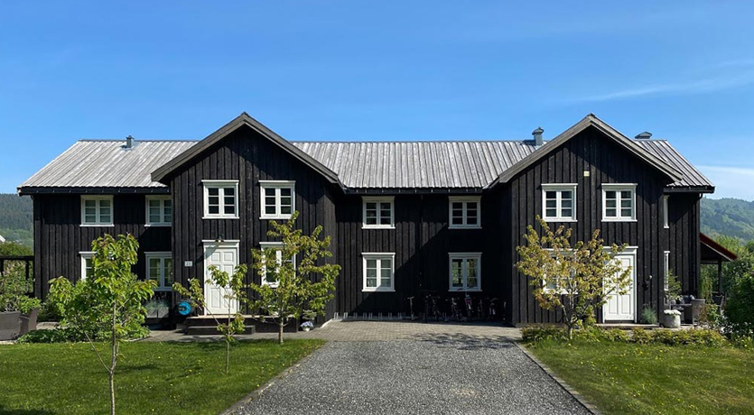Våningshus. Tretak i natur mot svart kledning, på gården hos Marte Helgetun.