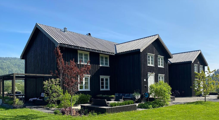 Våningshus. Tretak i natur mot svart kledning, på gården hos Marte Helgetun.