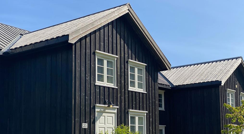 Våningshus. Tretak i natur mot svart kledning, på gården hos Marte Helgetun.