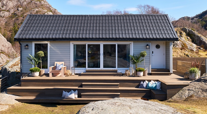 Eventyrlig oppussing, episode 3, sesong 7. Oversiktsfoto av ferdig oppusset hytte. Lekker terrasse i MøreRoyal grå.