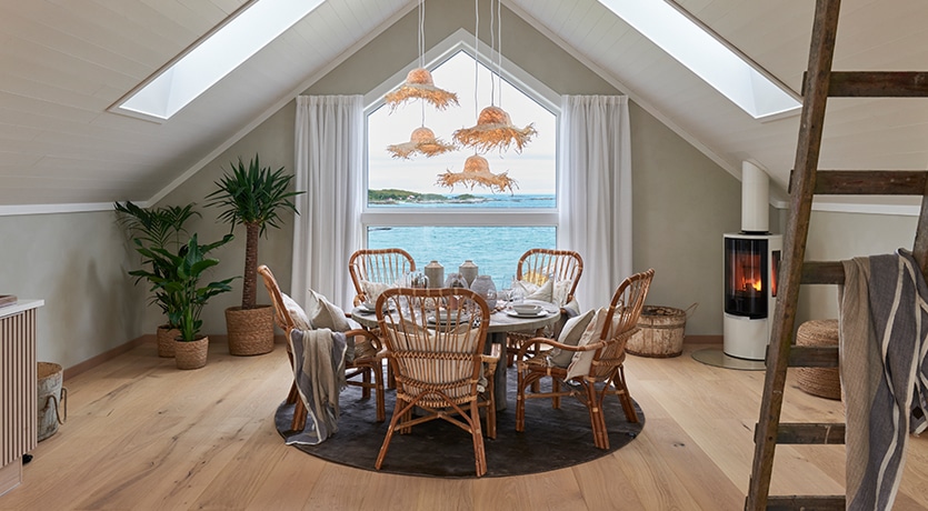 Eventyrlig Oppussing - Sommarøy - stue inne på låven. Spisebord med stoler. Lamper av stråhatter.